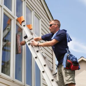 a man on a ladder cleaning a window